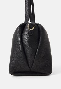 Svart läder axelväska med en texturerad yta, rund form och en guldring som accent på remmen för stängning.