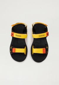 Sorte og gule sandaler med justerbare stropper, gummisåler og teksturert såle. Har Kappa-logo på stroppene. Holdbart design.