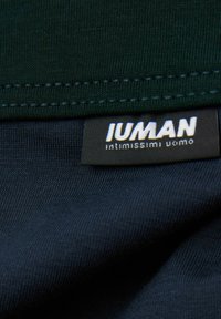 Mörkgrön och marinblå tyg, slät textur med synlig sömnad. Etiketter visar 'IUMAN' och 'intimissimi uomo' i vitt på svart bakgrund.