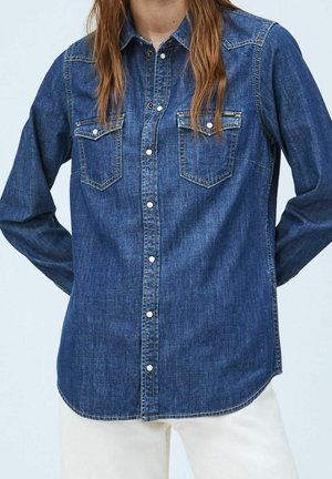Denim blouse in donkerblauw, met lange mouwen, twee borstzakken, knoopsluiting aan de voorkant en een getailleerde pasvorm met afgeronde zoom. Zachte textuur en klassiek ontwerp.