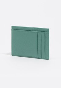 Un tarjetero de cuero texturizado en verde menta con cinco ranuras y un diseño rectangular y delgado, que presenta una costura ordenada a lo largo de los bordes.