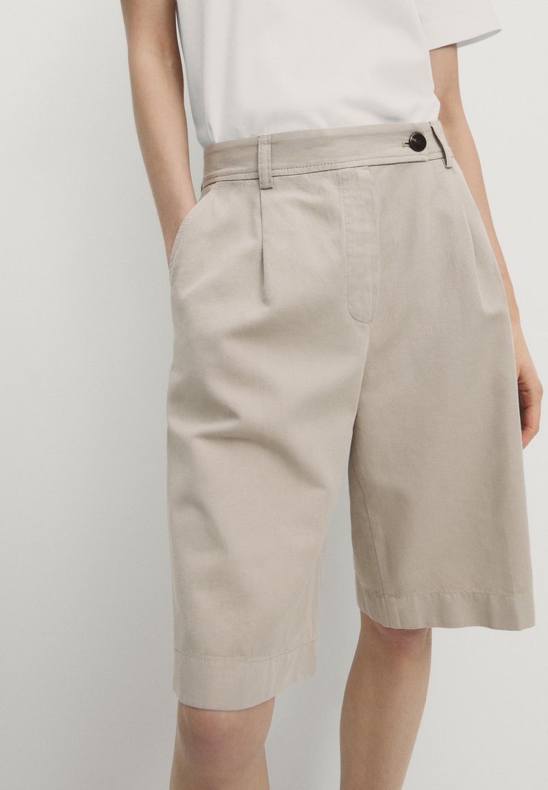 Beige bomuldsshorts med lige snit, synlige sidelommer og en enkelt knaplukning i taljen, med foldet kantdetalje.
