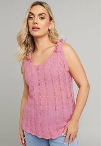 Rosa stickad linnen med ribbat mönster, som har axelband och en lös passform. Mönstret inkluderar vertikala ränder och detaljer med öppen väv.