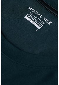 T-shirt z jedwabiu modalowego w ciemnozielonym kolorze, z okrągłym dekoltem i subtelną teksturą. Widoczna metka z informacjami o marce i rozmiarze (L).