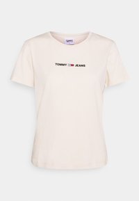Camiseta de algodón color crema con mangas cortas, que presenta el texto "TOMMY" y "JEANS" en bordado negro, rojo y blanco atraviesando el pecho.