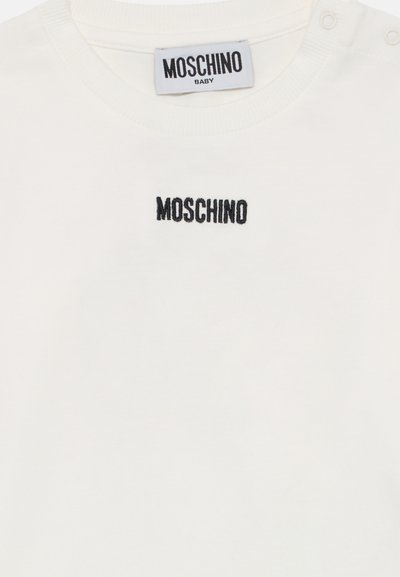 Witte katoenen baby t-shirt met korte mouwen, met een zwart geborduurd "MOSCHINO" logo op de voorkant en drukknopen op de schouder.