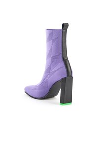 Lila högklackad stövel med en strukturerad stickad ovandel, spetsig tå och en kraftig svart klack med en grön bas.