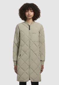 Cappotto lungo trapuntato di colore beige chiaro con polsini a costine, chiusura con zip, tasche laterali e una tasca sul petto con dettagli del logo.