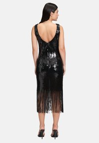 Czarna sukienka wyszywana cekinami, z głębokim dekoltem na plecach, do kolan, z frędzlami i bez rękawów. Gładka tekstura z odblaskowymi detalami.