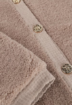 Beige fleece vest met een gestructureerde stof, voorzien van een gladde gebreide rand en gouden decoratieve knopen. Zacht, warm en gezellig ontwerp.