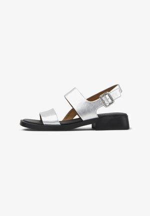 Sandal in pelle argentata con due ampie cinghie, fibbia regolabile, punta rotonda e tacco a blocco nero opaco. Sole piatto e insole testurizzata.