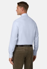 Hellblaues Langarmhemd mit klassischem Kragen, Knopfmanschetten und glatter Textur, kombiniert mit braunen Cordhosen.