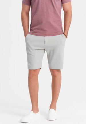 Gray shorts made of textured fabric, featuring a flat front and side pockets. Paired with a short-sleeve, pink crew-neck shirt and white slip-ons.