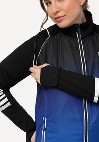 Sort og blå sportsjakke med lynlås foran, kontrasterende hvide striber på ærmerne, og en lynlåslomme på siden.