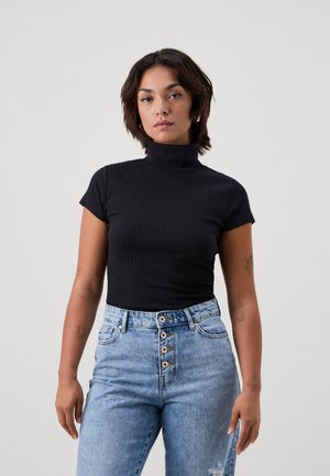 Must have mustriba turtleneck, mille varrukate ja lühikeste käistega, kantud helesiniste kõrge taljega teksadega, millel on ees nööbid ja kerge kulumine.