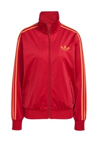 Röd zip-up jacka i slätt material, med orangea ränder på axlarna och ärmarna, samt Adidas-logotypen i orange på övre vänster sida.