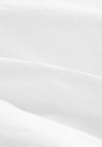Gros plan de couches superposées de tissu blanc lisse montrant la texture et des plis doux.