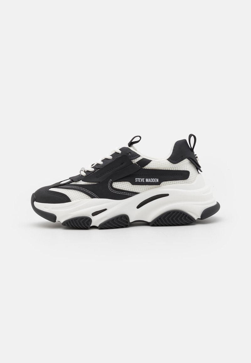 Black and white sneaker featuring a mesh upper, cushioned sole, and textured rubber outsole. Includes laces and a pull tab on the heel.