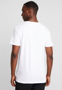 White cotton T-shirt with short sleeves, round neckline, and relaxed fit. Simple design with no visible patterns or accents.