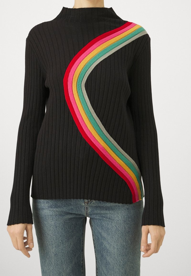 Černý žebrovaný svetr s vysokým límcem, který má diagonální pruhovaný vzor v červené, růžové, žluté, zelené a šedé.