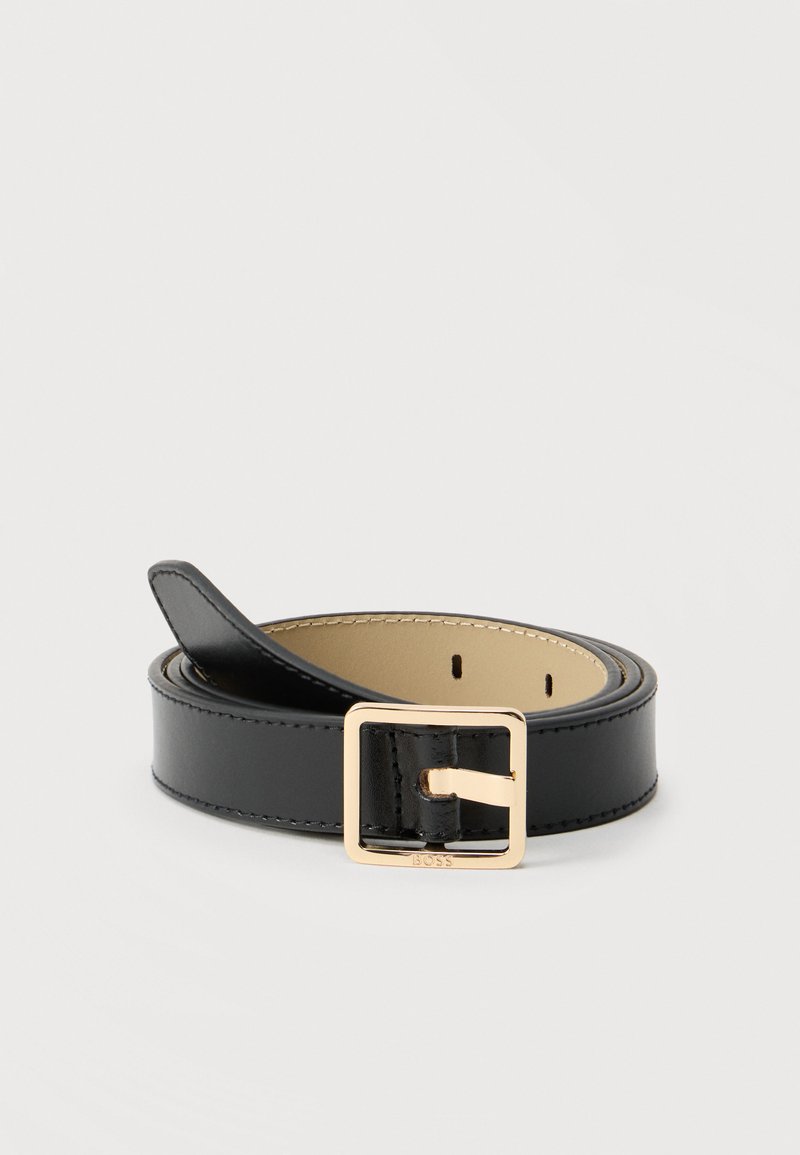 Ceinture en cuir noir enroulée avec une boucle carrée dorée et des coutures visibles sur un fond neutre.