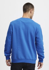 Felpa blu realizzata in tessuto morbido, con colletto rotondo, maniche lunghe e polsini a coste, caratterizzata da un design semplice e priva di loghi visibili.