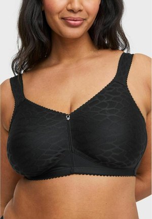 Vrouw die een zwarte draadloze beha draagt met een patroon, brede bandjes en een klein vrouwelijke symbool bedeltje aan de voorkant in het midden.