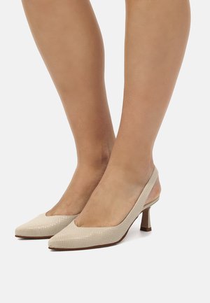 Zapatos de tacón alto beige con una superficie texturizada, punta afilada y parte trasera abierta. Presentan un tacón delgado y de altura media.