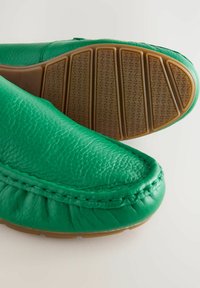 Bottines en cuir vert avec une tige texturée, des détails cousus, et une semelle en caoutchouc avec un motif en zigzag pour une meilleure adhérence.