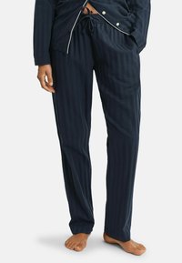 Navyblauw gestreept pyjama set met een top met knopen en witte bies en broek met elastische tailleband en een comfortabele pasvorm. Zachte stoftextuur.