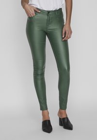 Gröna, blanka skinny jeans i ett smidigt material med en figurnära design. Med knäppning och dragkedja, framfickor och låg midja.