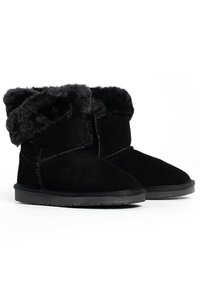 Botas de ante negras hasta el tobillo con un puño de piel de pelo negro suave, puntera redondeada y suela de goma negra texturizada. Diseño sencillo sin hardware visible.