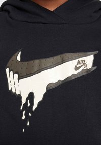 Hanorac bleumarin cu un logo mare Nike SB, care picură, în alb și gri, texturat cu un model cu puncte pe secțiunea superioară.