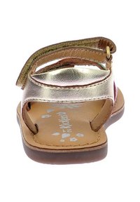 Sandalía infantil metálica dorada con tira de cuero marrón, parte trasera abierta y plantilla con patrón floral. Cierre de velcro para un ajuste ajustable.