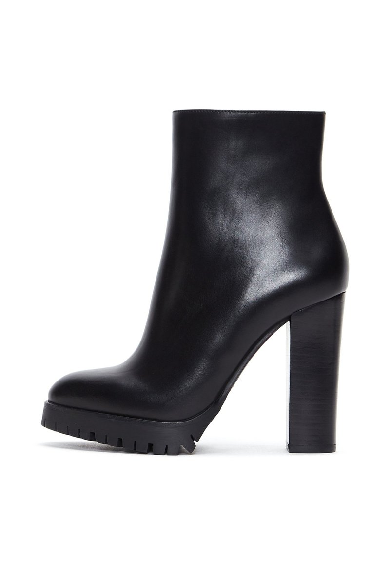 Botte de cheville en cuir noir avec un haut talon bloc et un bout profilé. Semelle épaisse avec un relief robuste. Texture lisse et brillante.