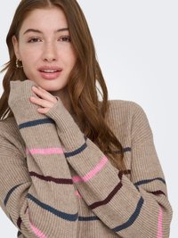 Pull beige avec des rayures horizontales roses, bleues et bordeaux. Texture tricotée, manches longues avec trous pour les pouces, coupe ample.