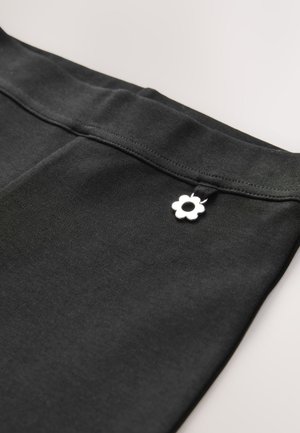 Țesătură elastică neagră cu o talie netedă și un mic charm argintiu în formă de floare.