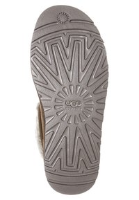 UGG-schoenzool met een gestructureerd grijs rubberen oppervlak met een zonnestraalpatroon, merklogo en details voor verbeterde grip.