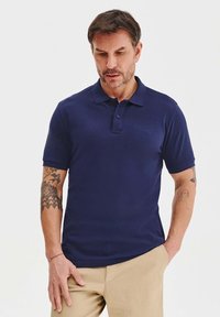Granatowa koszulka polo z kołnierzykiem, krótkimi rękawami i trzema guzikami. Posiada gładką fakturę i subtelne logo na piersi.