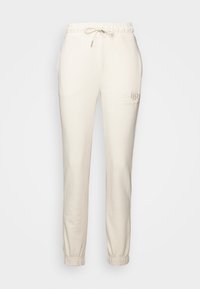 Pantaloni della tuta color crema realizzati in tessuto morbido, con vita elasticizzata e cordoncino di regolazione, e polsini a costine alle caviglie.