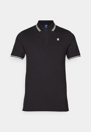 Schwarzes Poloshirt aus Baumwolle mit weißen Streifenakzenten am Kragen und an den Ärmeln; verfügt über ein kleines Logo auf der Brust.