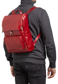 Zaino in pelle rossa con scomparto principale con zip, tasca frontale e spallacci regolabili. Texture liscia e lucida con hardware minimale.
