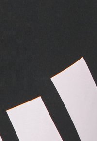 Černá látka se třemi bílými obdélníkovými pruhy seřazenými diagonálně z levého dolního rohu do pravého horního.