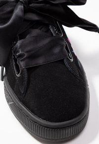 Svarta mockaskor med rund tå, utrustade med en tjock gummisula och breda svarta satinsnören. Metalldetaljer förbättrar snörningen.