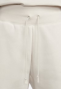 Pantalones de chándal beige con cinturilla acanalada, cordón con extremos ajustables y tejido suave y texturizado para mayor comodidad.