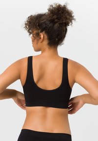 Schwarzer Sport-BH mit breiten Trägern, abgerundetem Rücken und glatter Textur. Bietet eine enge Passform ohne äußere Befestigungen oder Verzierungen.