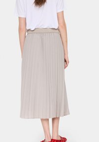 Gonna midi plissettata in tessuto beige chiaro con vita elastica. Caratterizzata da una consistenza morbida e un design fluido, raggiunge la lunghezza a metà polpaccio.