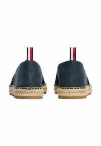 Espadrillas in denim con tomaia blu trama, suola in corda di juta e linguetta posteriore con righe rosse e bianche per una facile indossabilità.