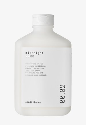 Weißflasche aus Plastik mit rundem Design und Klappdeckel. Das Etikett zeigt schwarzen Text, der das Produkt als Conditioner kennzeichnet und die Inhaltsstoffe aufführt.