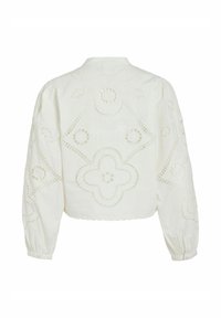 Blouse blanche à manches longues avec manches bouffantes, ourlet festonné et motif brodé floral en découpe au dos et sur les manches.